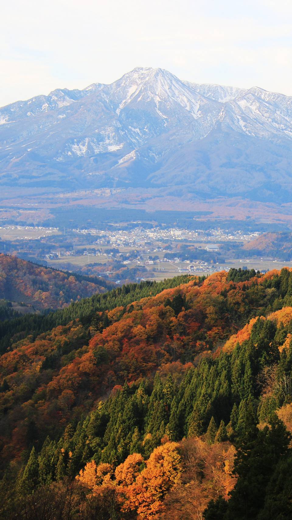 紅葉に包まれた山あいと雪を残す山々